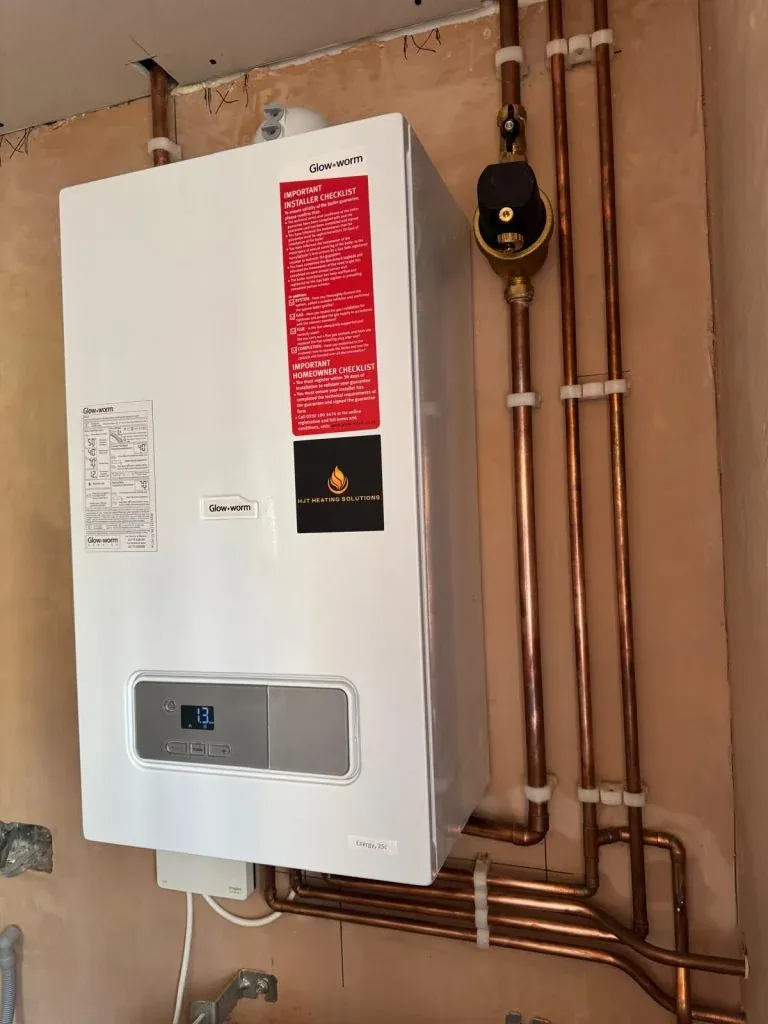 A white boiler with HJT Heating Solutions branding and copper pipework
