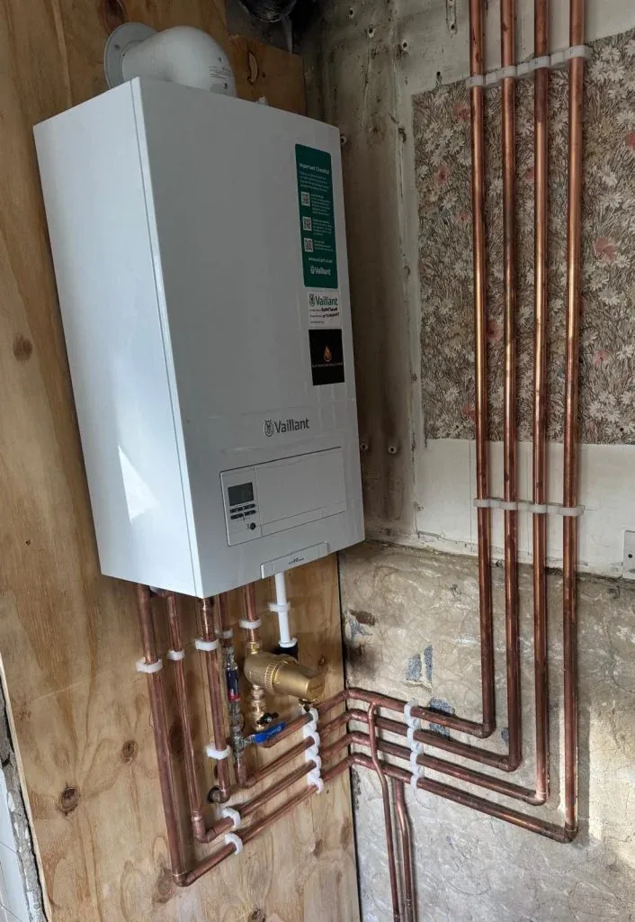 A wall-mounted boiler with exposed copper heating pipework